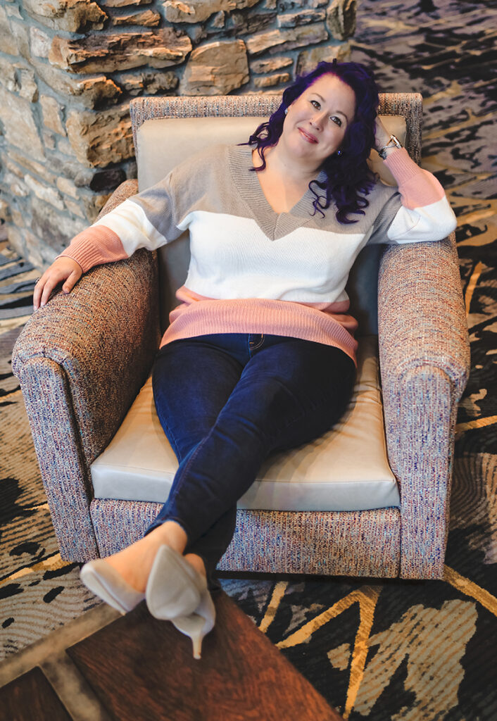 Stephanie Moutei sitting in a chair, feet crossed, smiling